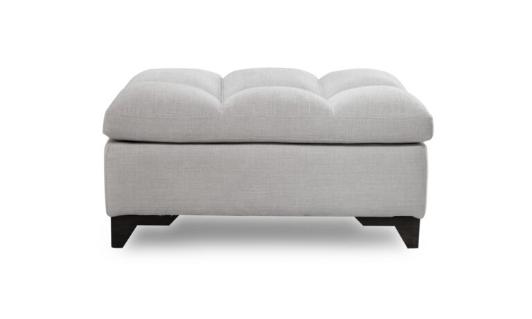 Puff Vitaro Plus de la marca Aristas, visto en perspectiva frontal. Un diseño moderno y minimalista, con una estructura rectangular, y patas en madera color Chocolate.