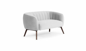 Vista diagonal del Sofá Kaira de Aristas. Un diseño de líneas limpias y elegantes, con un tapizado en tela de tono neutro y un asiento y espaldar acolchados.