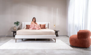 Cama Florencia de la marca Aristas vista en perspectiva frontal. Un diseño elegante y clásico, con un cabecero alto y acolchado de líneas limpias y una base tapizada en tela suave.