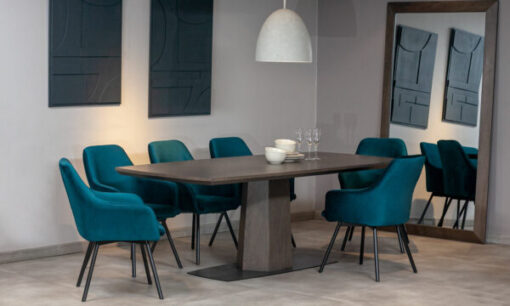 Mesa Comedor Nápoles con 8 Sillas Turín P/N de la marca Aristas vista en diagonal. La mesa tiene una forma rectangular de acabado liso en madera color Ceniza, y, las sillas Turín cuentan con un respaldo alto y acolchado de color Nobuck Marino.