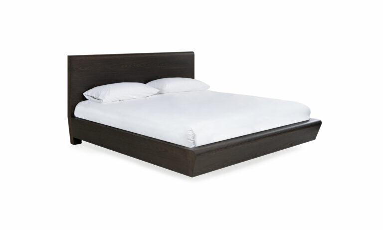 Vista diagonal de la Cama Nebraska de la marca Aristas. Esta cama destaca por su estructura robusta y diseño elegante. Tiene un cabecero alto y amplio, con una base que presenta una estructura sólida de líneas rectas.
