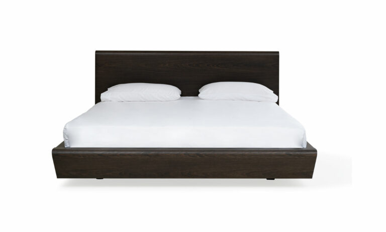 Vista frontal de la Cama Nebraska de la marca Aristas. Esta cama destaca por su estructura robusta en madera color Olmo. El cabecero es alto y amplio, mientas que la base presenta una estructura sólida de líneas rectas.
