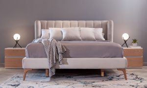 Cama Florencia de la marca Aristas vista en perspectiva frontal. Un diseño elegante de líneas limpias, con un cabecero alto, acabado en tela suave y patas de estilo clásico.