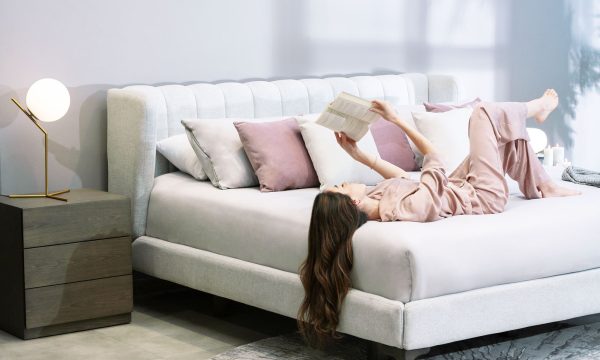 Cama Florencia de la marca Aristas vista en perspectiva diagonal. Presenta un diseño elegante que destaca por su cabecero alto y acolchado de líneas limpias. Tiene una base tapizada en tela suave y patas en madera de estilo clásico.