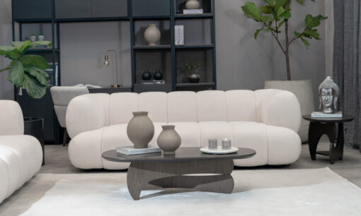 Vista frontal del Sofá Estambul de Aristas. Este sofá destaca por su diseño elegante y contemporáneo. Tiene tapizado en tela de color neutro, patas discretas en madera y líneas curvas.