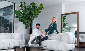 Vista diagonal del Sofá Estambul de Aristas. Este sofá destaca por su diseño elegante y contemporáneo. Tiene tapizado en tela de color Gante Crudo, patas discretas en madera y líneas curvas.