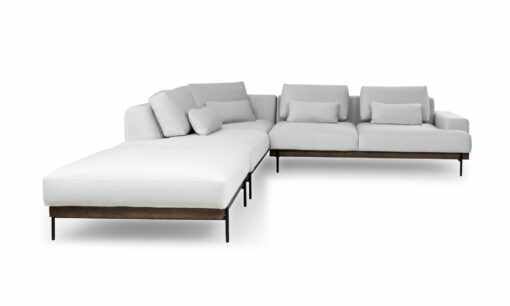 Vista frontal de la Sala En L Modular Maia con puff, de la marca Aristas. El sofá modular presenta un diseño contemporáneo, con un tapizado en tela suave de color neutro y líneas rectas que aportan elegancia. El puff, con el mismo estilo y material, complementa el conjunto.