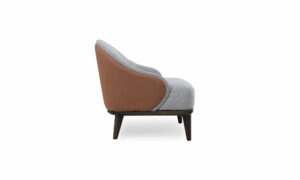 Poltrona Valencia de la marca Aristas vista en perspectiva lateral. Presenta un diseño moderno con un asiento y un respaldo acolchado, líneas limpias y bordes suaves en los colores de tela Nobuck Coñac y Derza Plata.