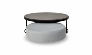 Juego de Mesa Centro Luna Mad 90 y Puff Luna 70 de la marca Aristas vista frontal. El conjunto presenta un diseño moderno y elegante, con formas redondeadas y acabados suaves en madera color Ceniza y tela color Derza Plata.