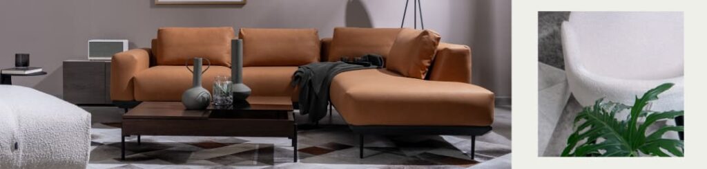 Sala con sofá modular en cuero caramelo y chaise longue junto a un detalle de poltrona blanca en bouclé con una planta