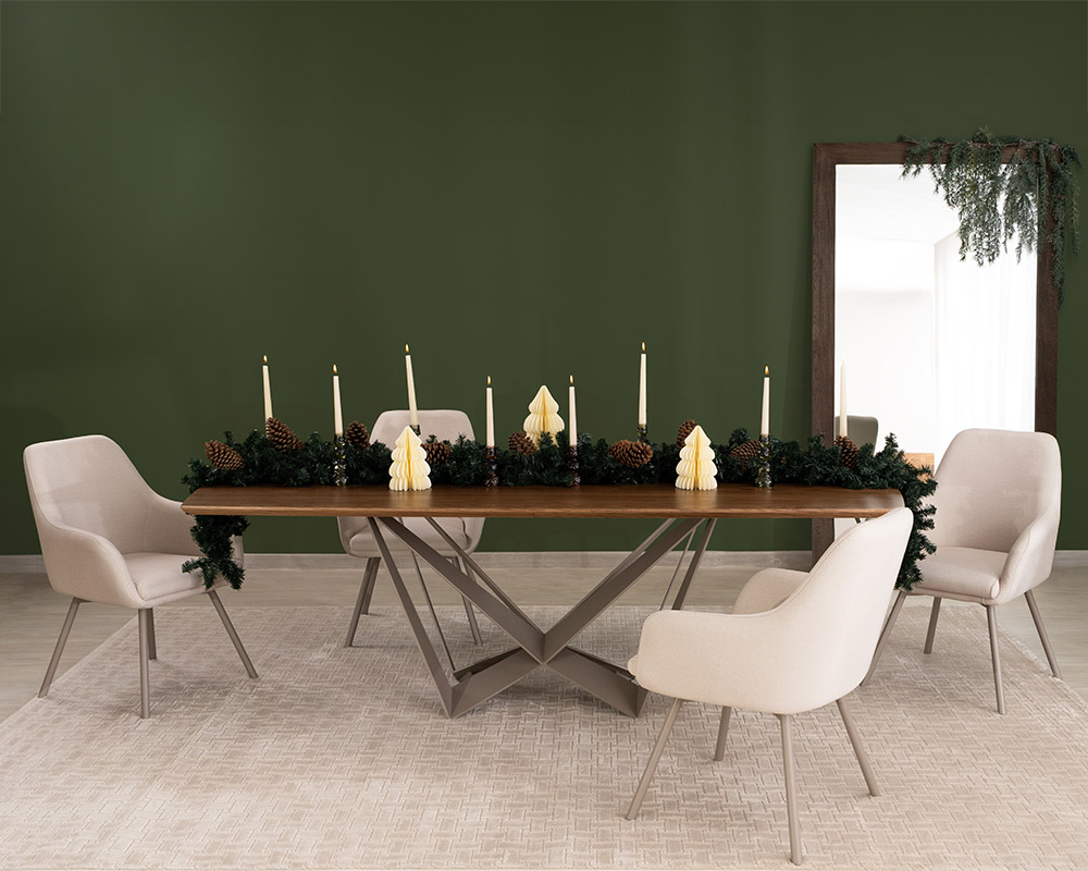 Comedor en nogal sobre muro verde con guirnalda de velas y piñas, sillas tapizadas en crudo y espejo de piso