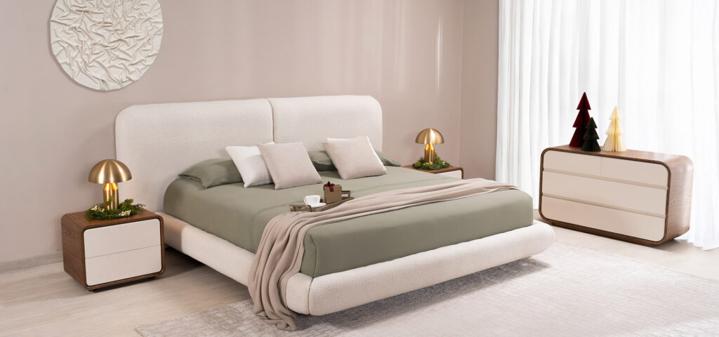 Dormitorio con cama de espaldar curvo en bouclé crudo, ropa de cama verde salvia y lámparas doradas, decorado con arbolitos de Navidad