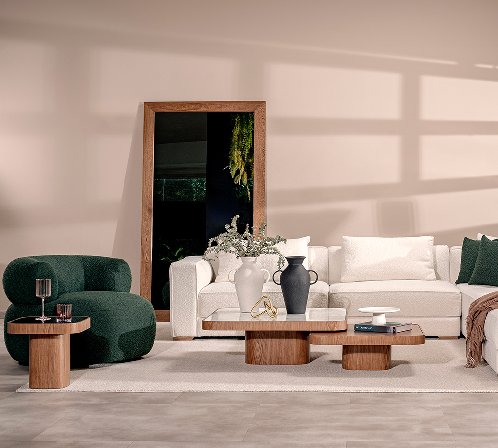 Sala en minimalismo cálido con sofá modular en bouclé blanco, poltrona verde oscuro y espejo de piso con marco en madera