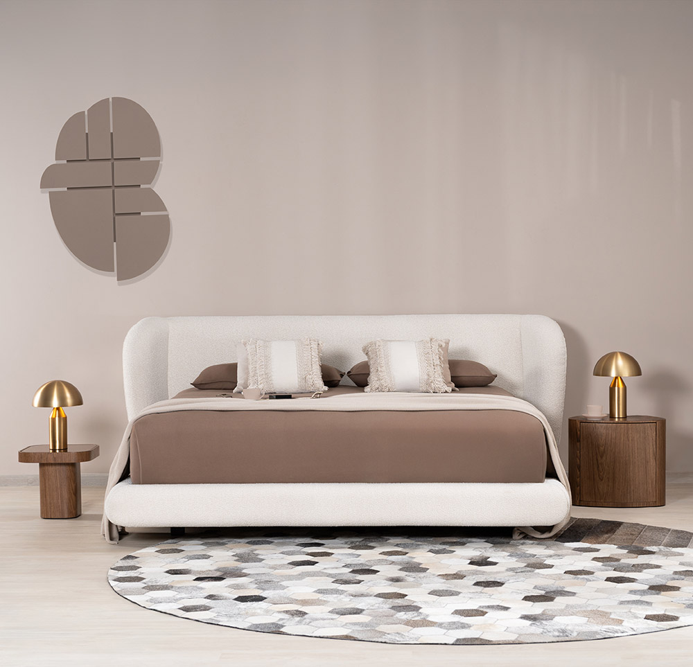 Dormitorio con cama de espaldar curvo en bouclé, ropa de cama en tonos tierra y mesas de noche cilíndricas en nogal