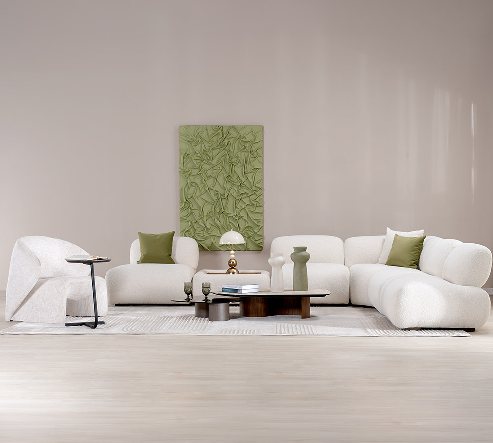 Sala con sofá modular en bouclé blanco y poltrona a juego, frente a una obra texturizada en verde y mesas de centro en madera