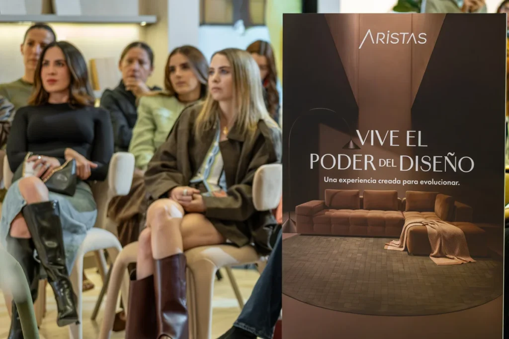 Invitados sentados escuchan la charla sobre los 23 años de Aristas junto a un cartel con el lema «Vive el poder del diseño»