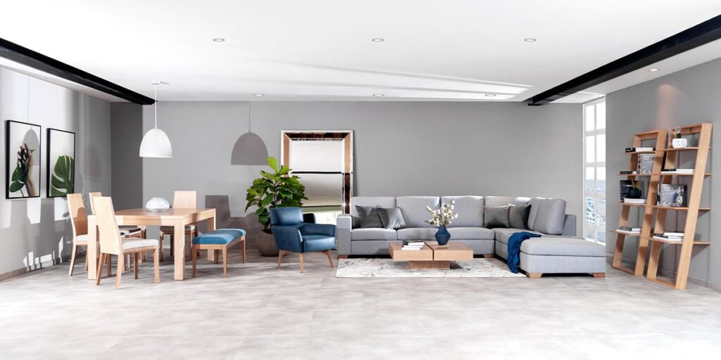 Espacio amplio con sala de sofá modular gris y poltrona azul, un comedor de madera y repisas, bajo un techo con vigas negras