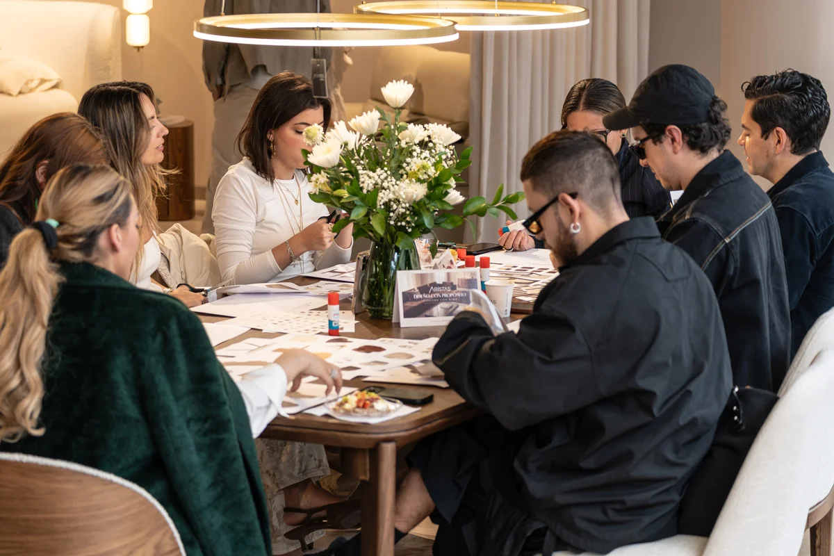 Invitados al encuentro por los 23 años de Aristas trabajando en sus moodboards alrededor de una mesa de madera con flores blancas, en el showroom de la Calle 81 en Bogotá