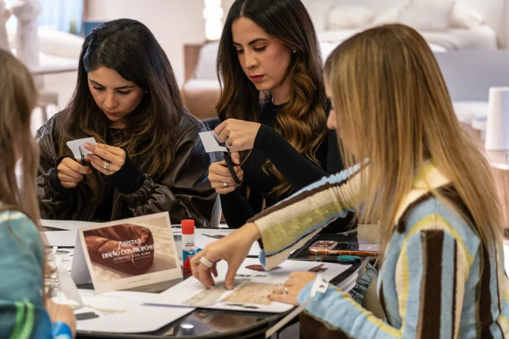 Tres invitadas recortan y pegan materiales para armar su moodboard durante la actividad creativa en el showroom de Aristas