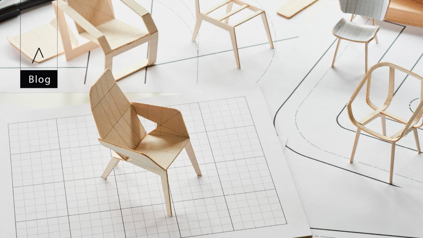 Maqueta de una silla de madera clara sobre un plano de diseño cuadriculado, junto a otras sillas de madera, con la palabra «Blog»