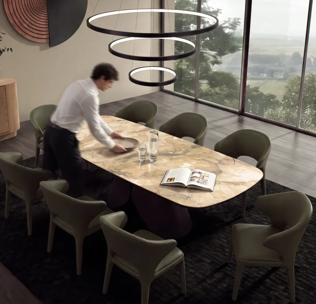 Comedor amplio con mesa de cubierta tipo mármol y sillas tapizadas en verde oliva, bajo lámparas circulares